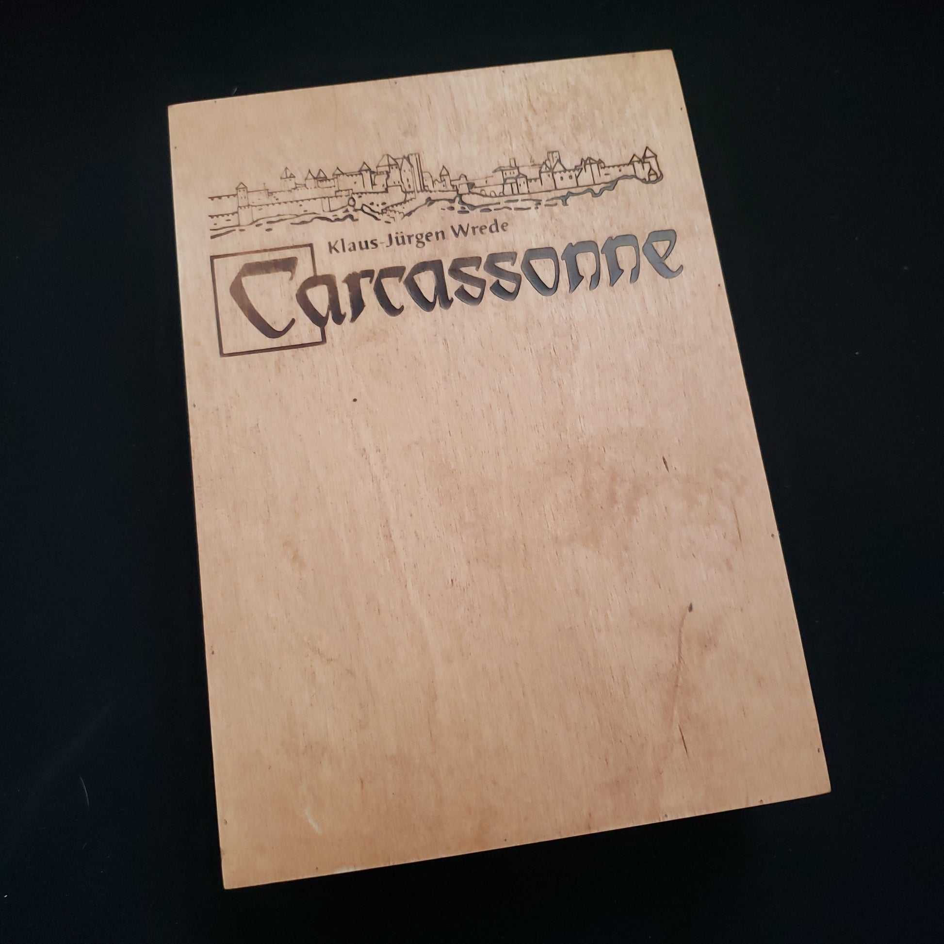 Image shows the front cover of the wooden box of the board game Carcassonne: the City