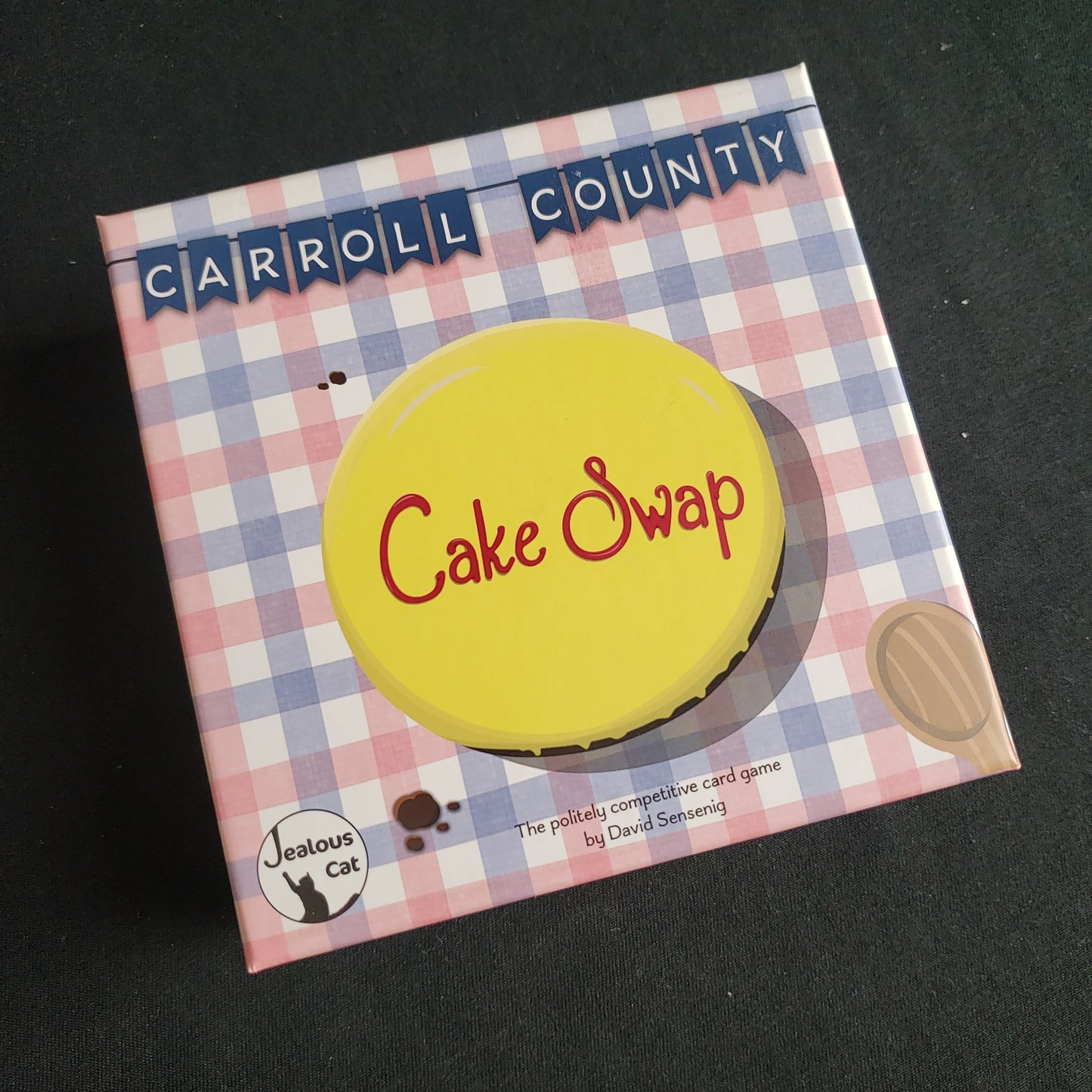 Image shows the front cover of the box of the Carroll County Cake Swap card game