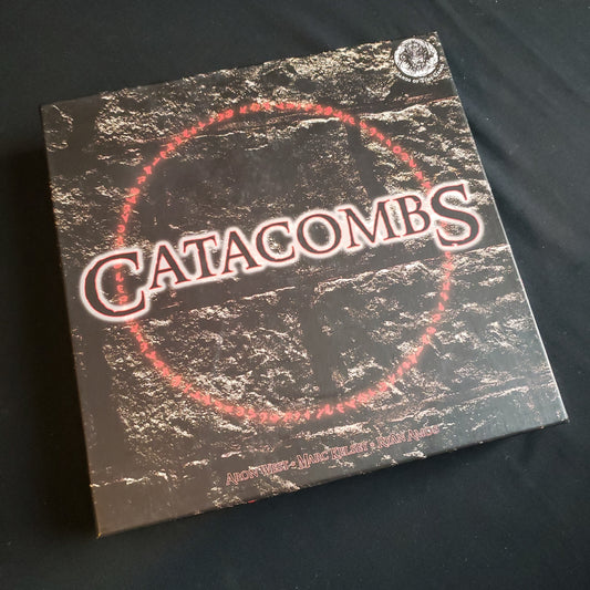 Image shows the front cover of the box of the Catacombs board game