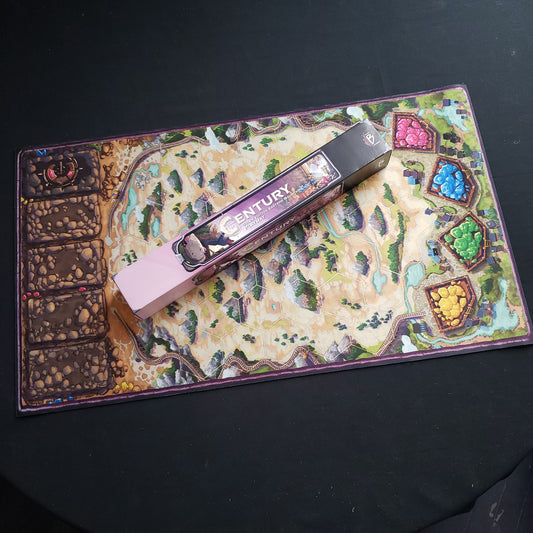 Image shows the neoprene playmat for the Century: Golem Edition - Eastern Mountains board game, with the box sitting on top of it.