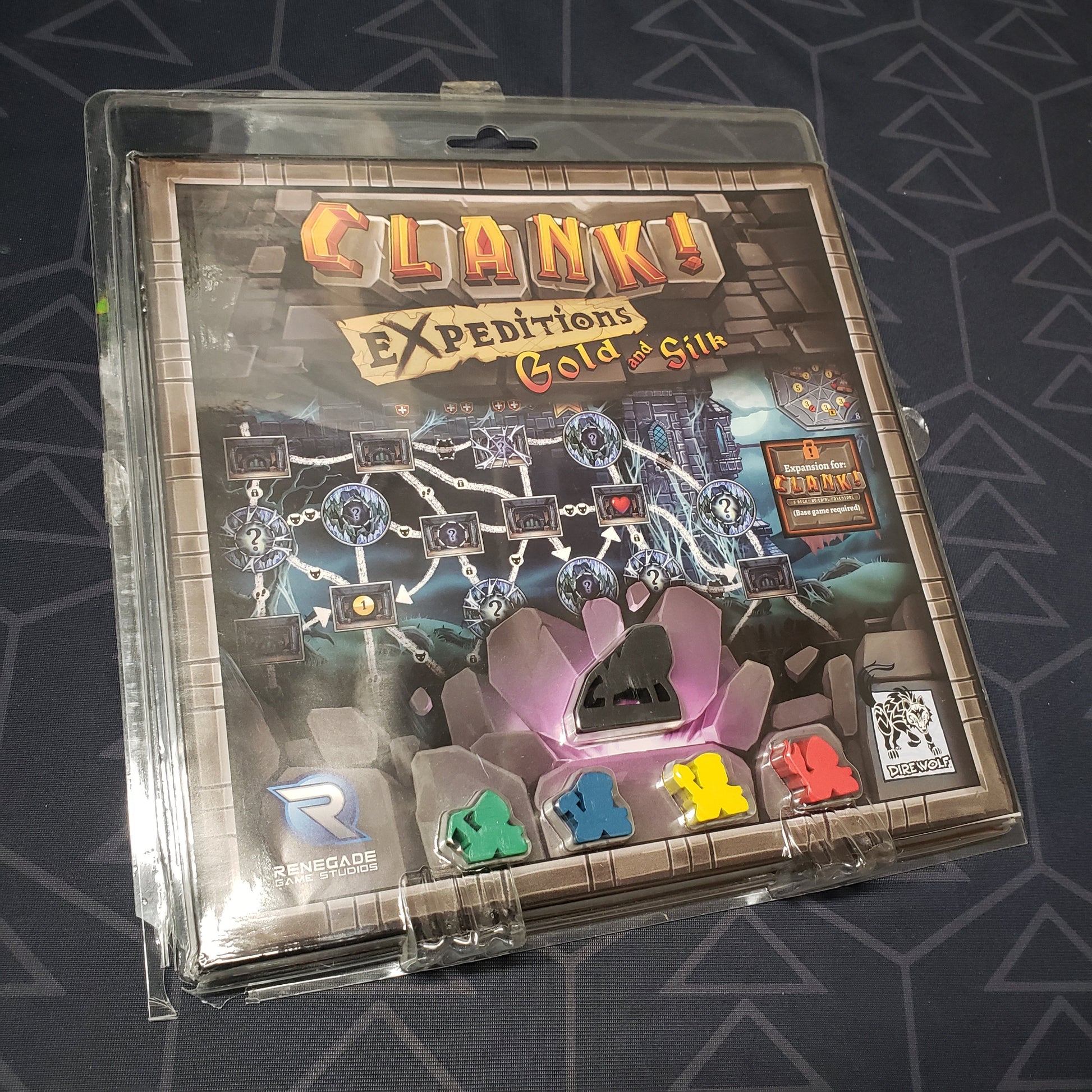 Image shows the front cover of the box of the Expeditions: Gold and Silk expansion for the board game Clank!