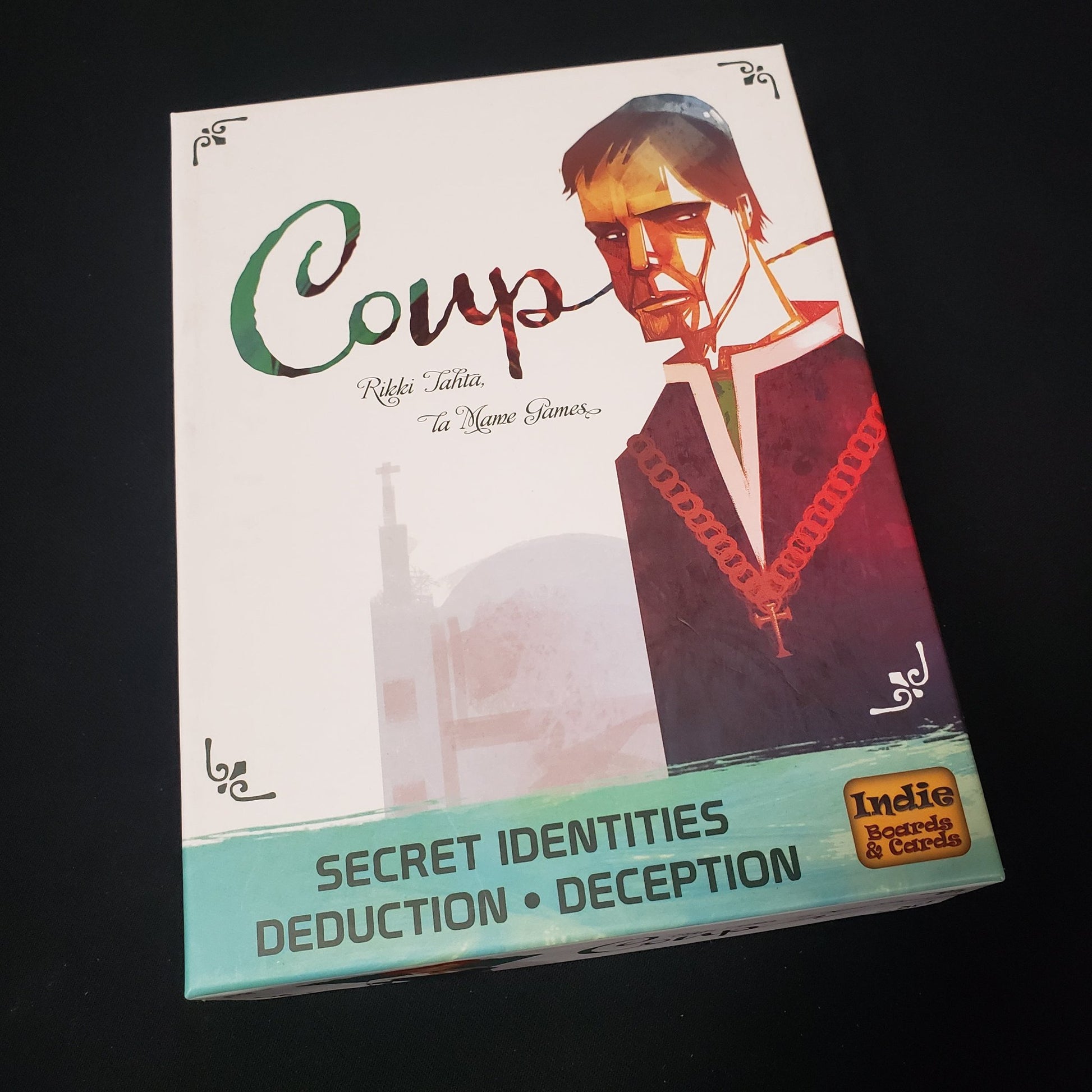 Image shows the front cover of the box of the deluxe edition of the card game Coup