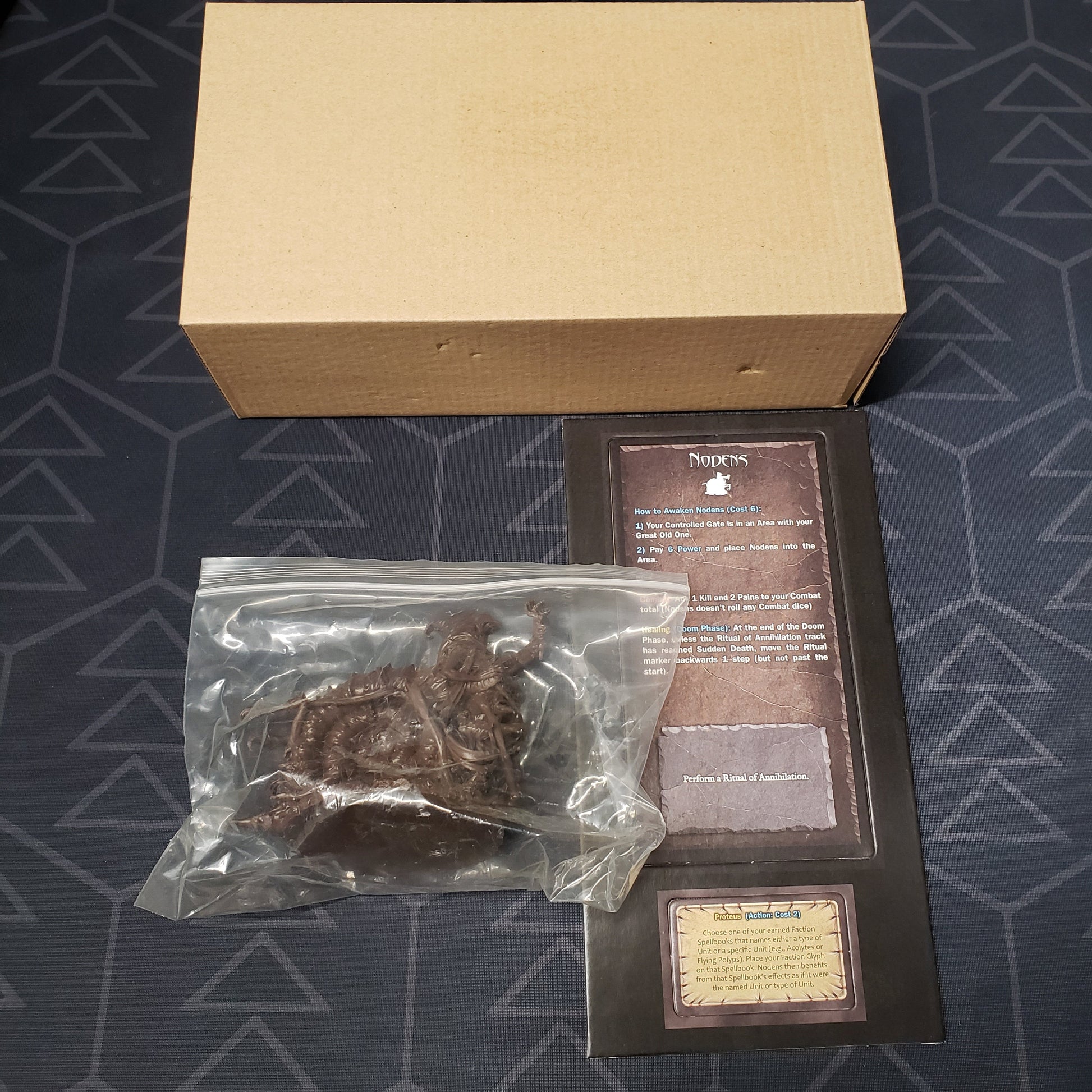 Image shows the cardboard box, miniature and cards for the Nodens expansion for the board game Cthulhu Wars