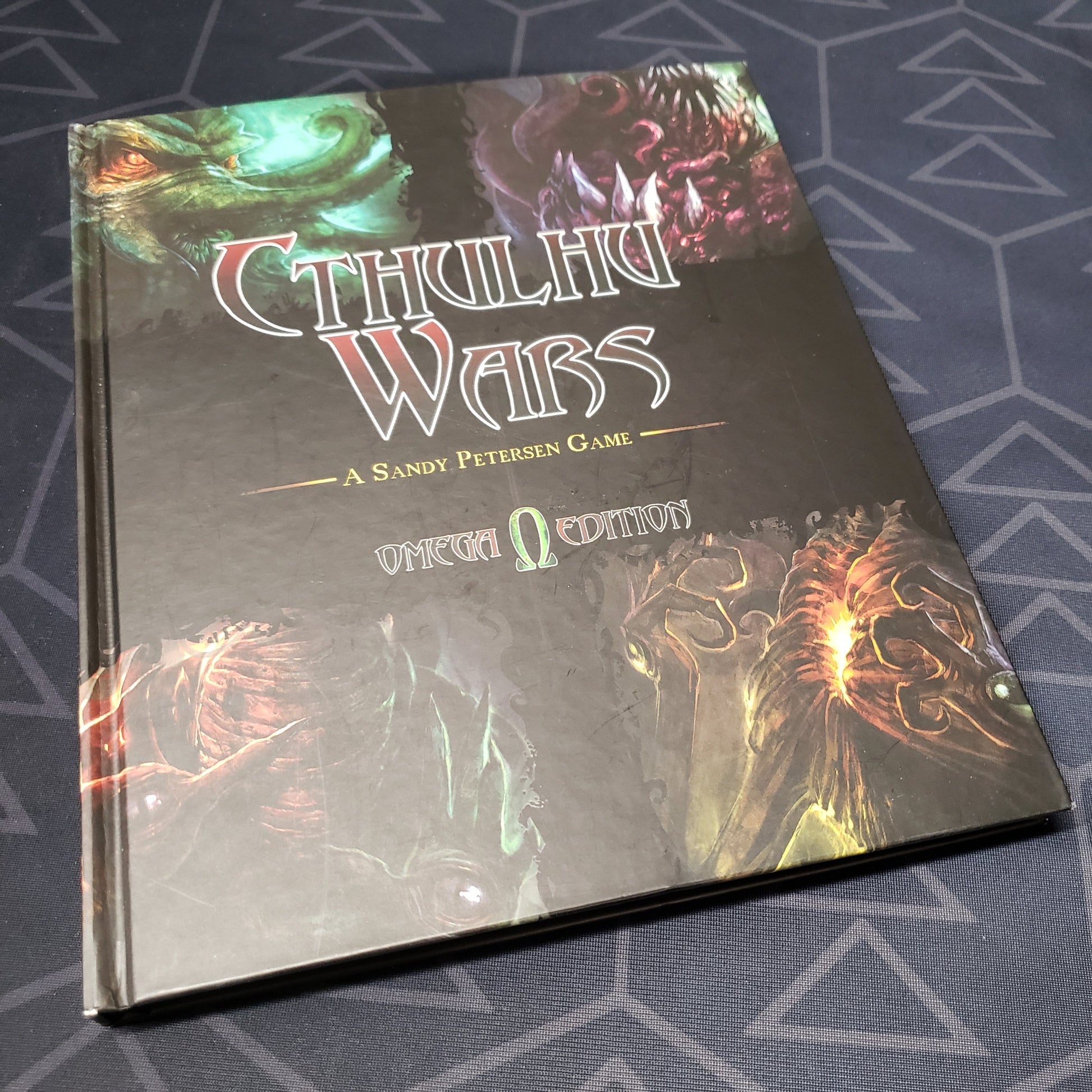 Image shows the front cover of the Omega Edition Master Rulebook for the board game Cthulhu Wars