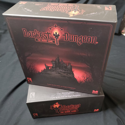 Image shows the front cover of one box stacked on top of the side of the miniatures box for the Darkest Dungeon board game