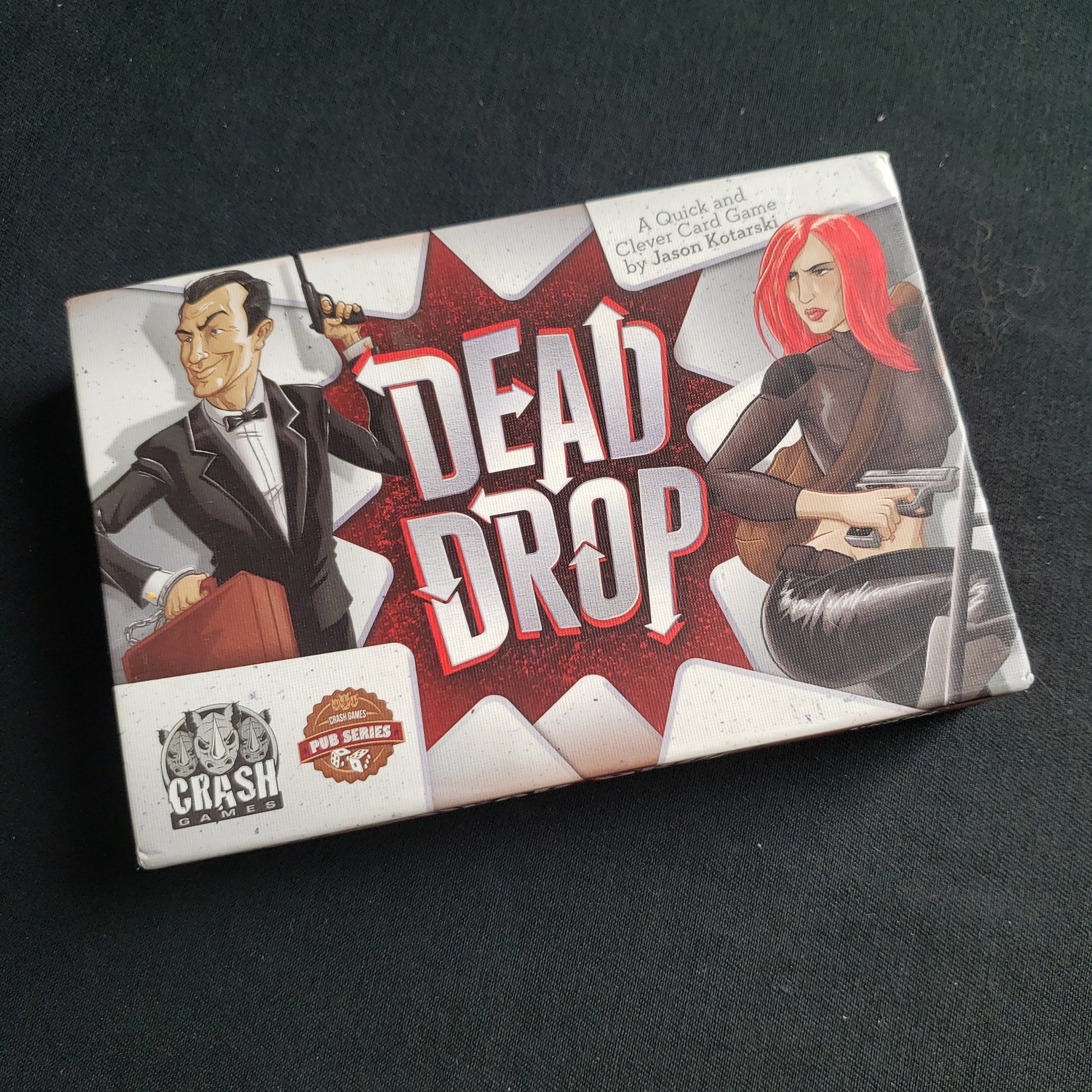 Image shows the front cover of the box of the Dead Drop card game