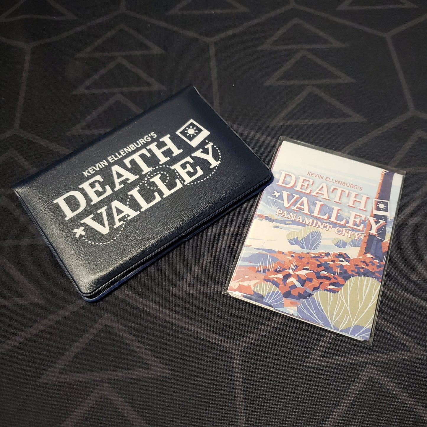 Image shows the front of the card wallet for the Death Valley card game, with the Panamint City expansion sitting next to it