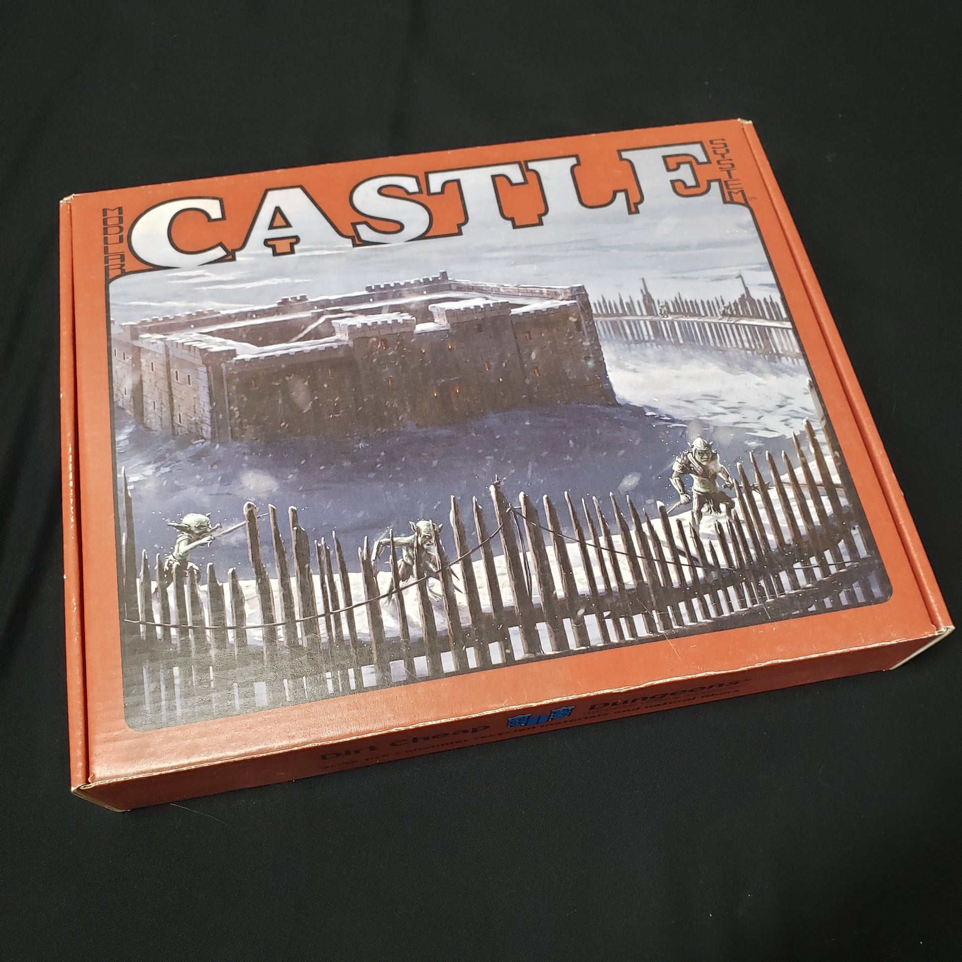 Image shows the front cover of the box of the Castle set for the Dirt Cheap Dungeons modular terrain system