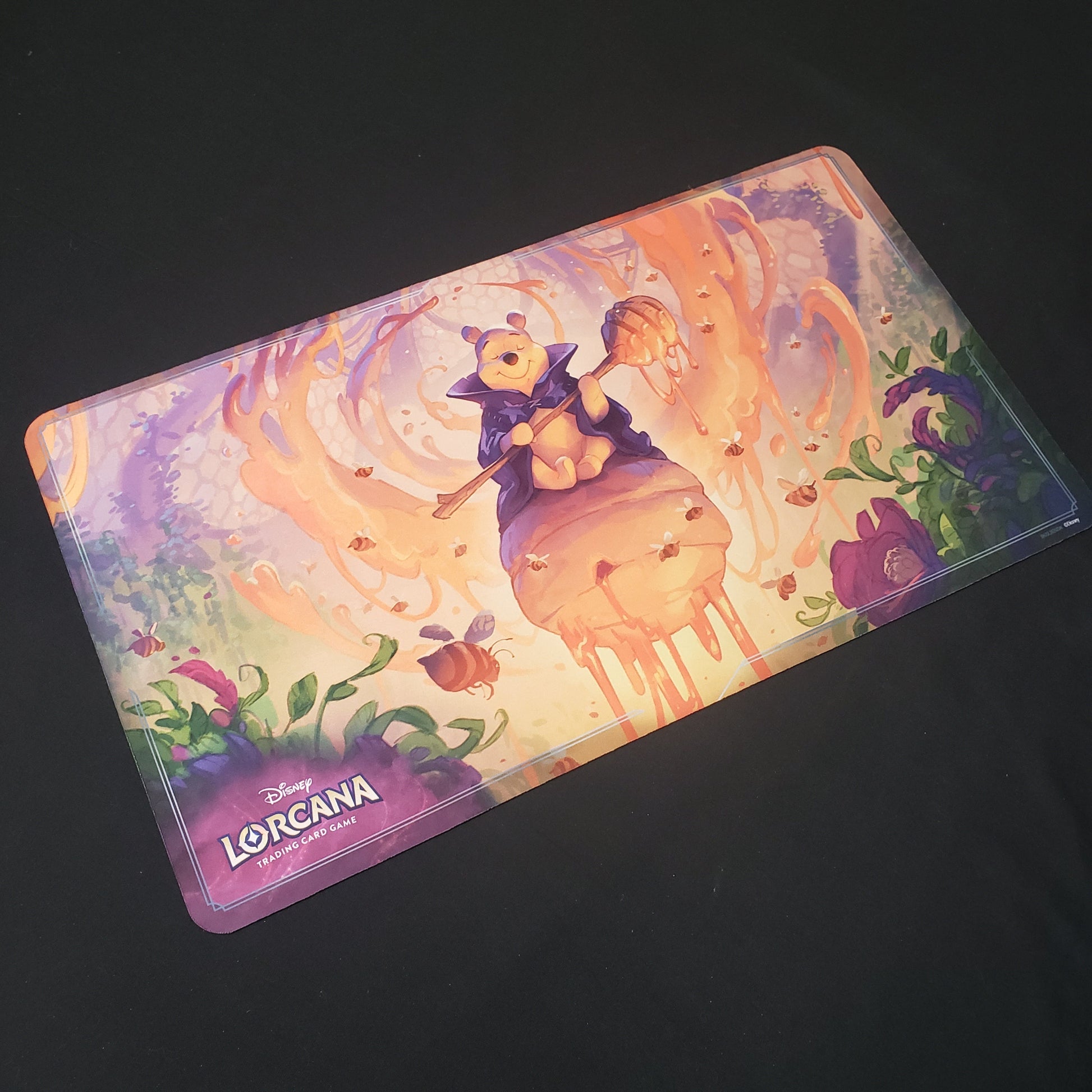 Image shows a playmat featuring Rise of the Floodborn: Winnie the Pooh, Hunny Wizard art for the Disney Lorcana card game