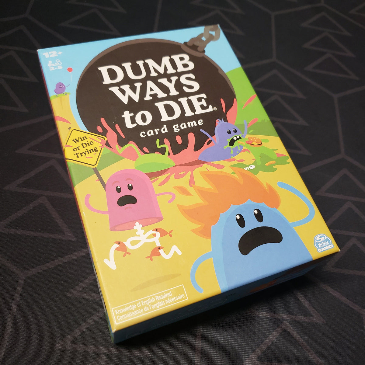 Image shows the front cover of the box for the Dumb Ways to Die card game