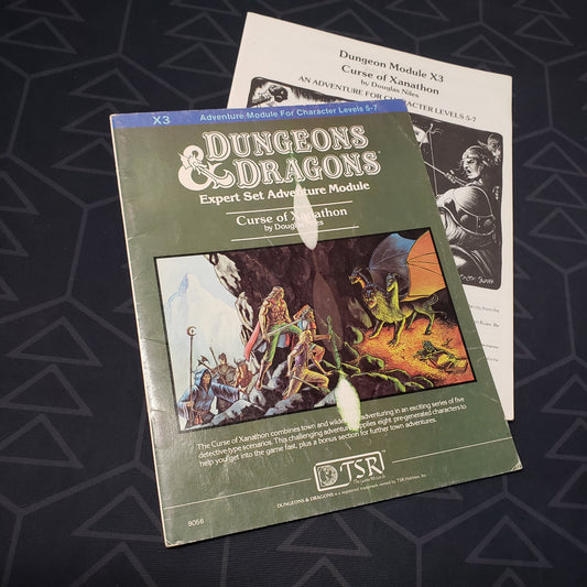 Image shows the front cover of the folio for the Curse of Xanathon adventure module for the roleplaying game Dungeons & Dragons 1E with the booklet fanned out