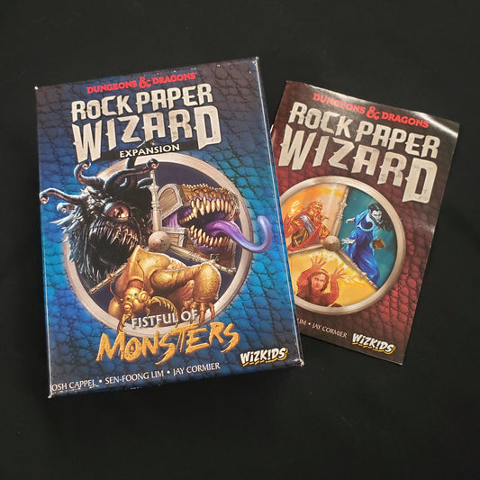 Image shows the front cover of the box of the Fistful of Monsters expansion for the card game Dungeons and Dragons: Rock Paper Wizard, sitting on top of the instructions for the base game