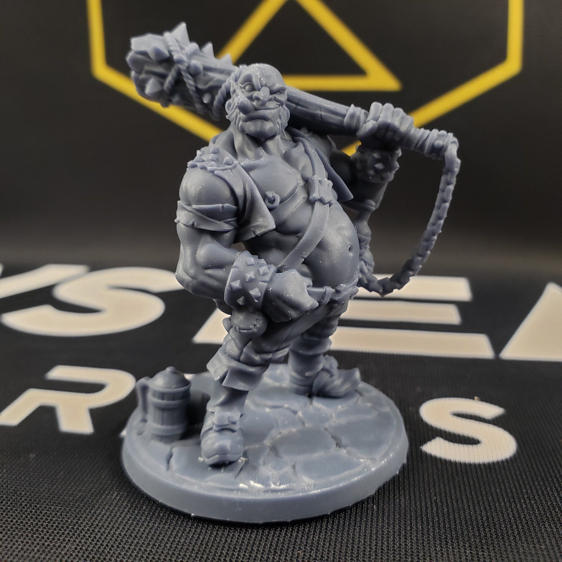 Image shows the front of a half-ogre gaming miniature holding a spiked club on his shoulder