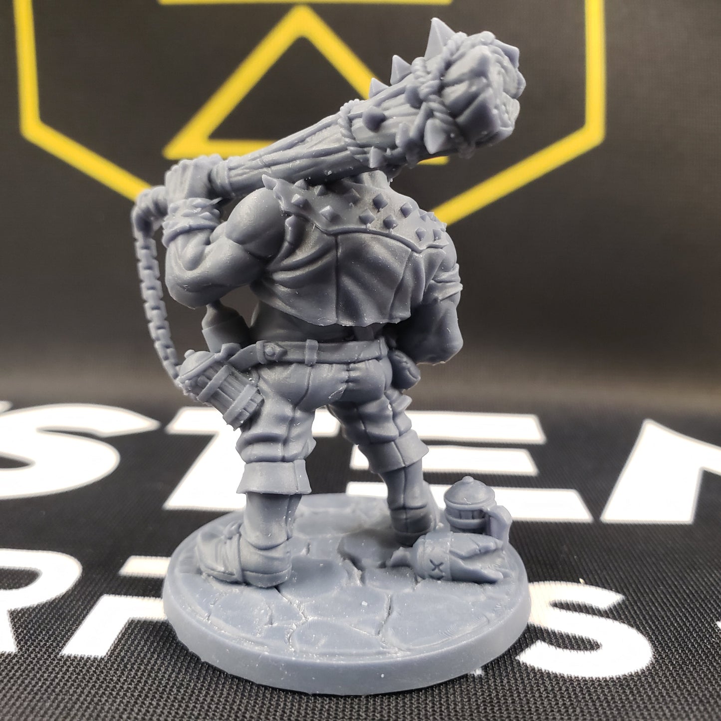 Image shows the back of a half-ogre gaming miniature holding a spiked club on his shoulder