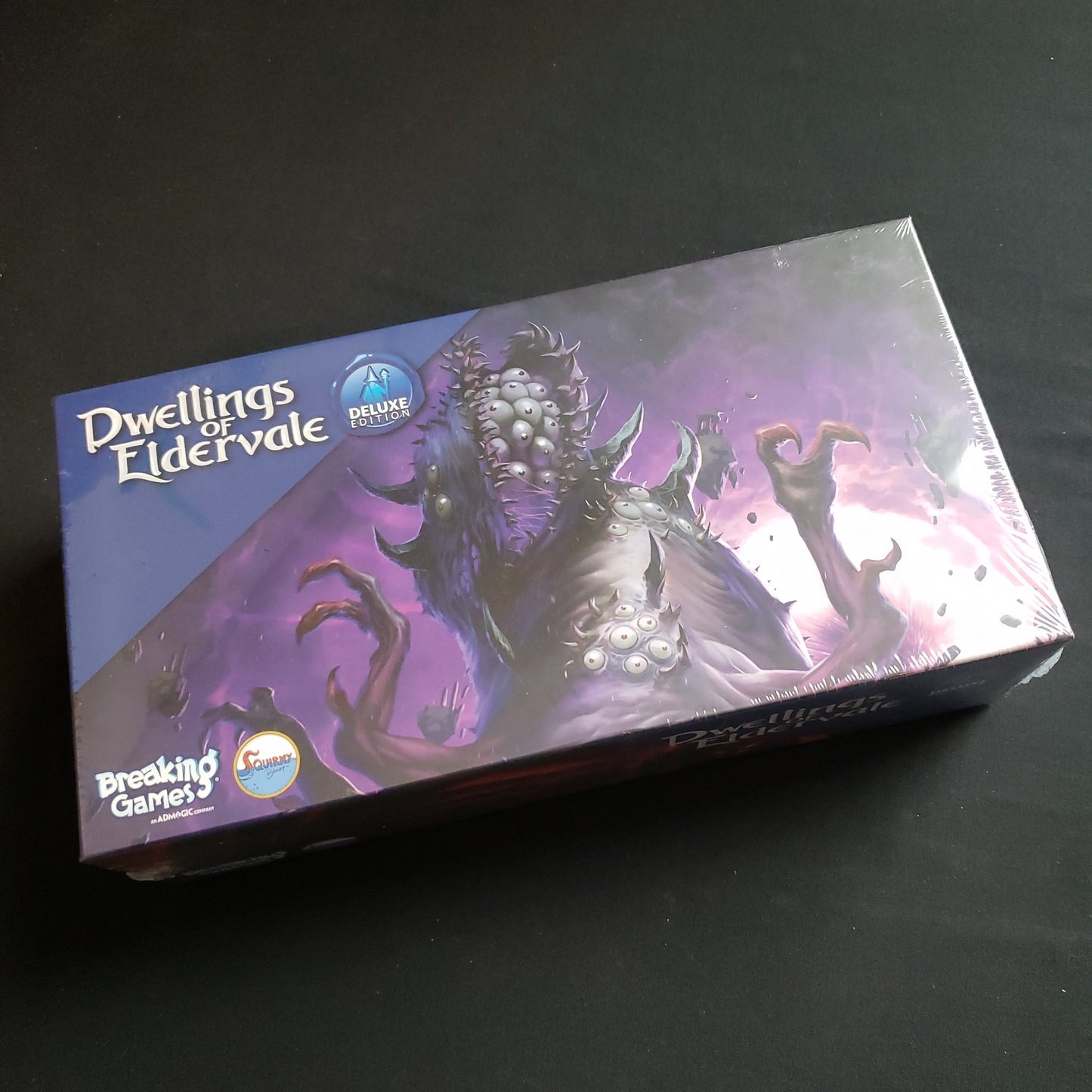 Image shows the front cover of the box of the deluxe Upgrade Pack for the board game Dwellings of Eldervale