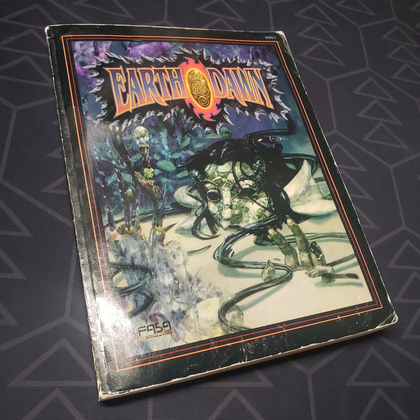 Image shows the front cover of the core rulebook for the roleplaying game Earthdawn 1E