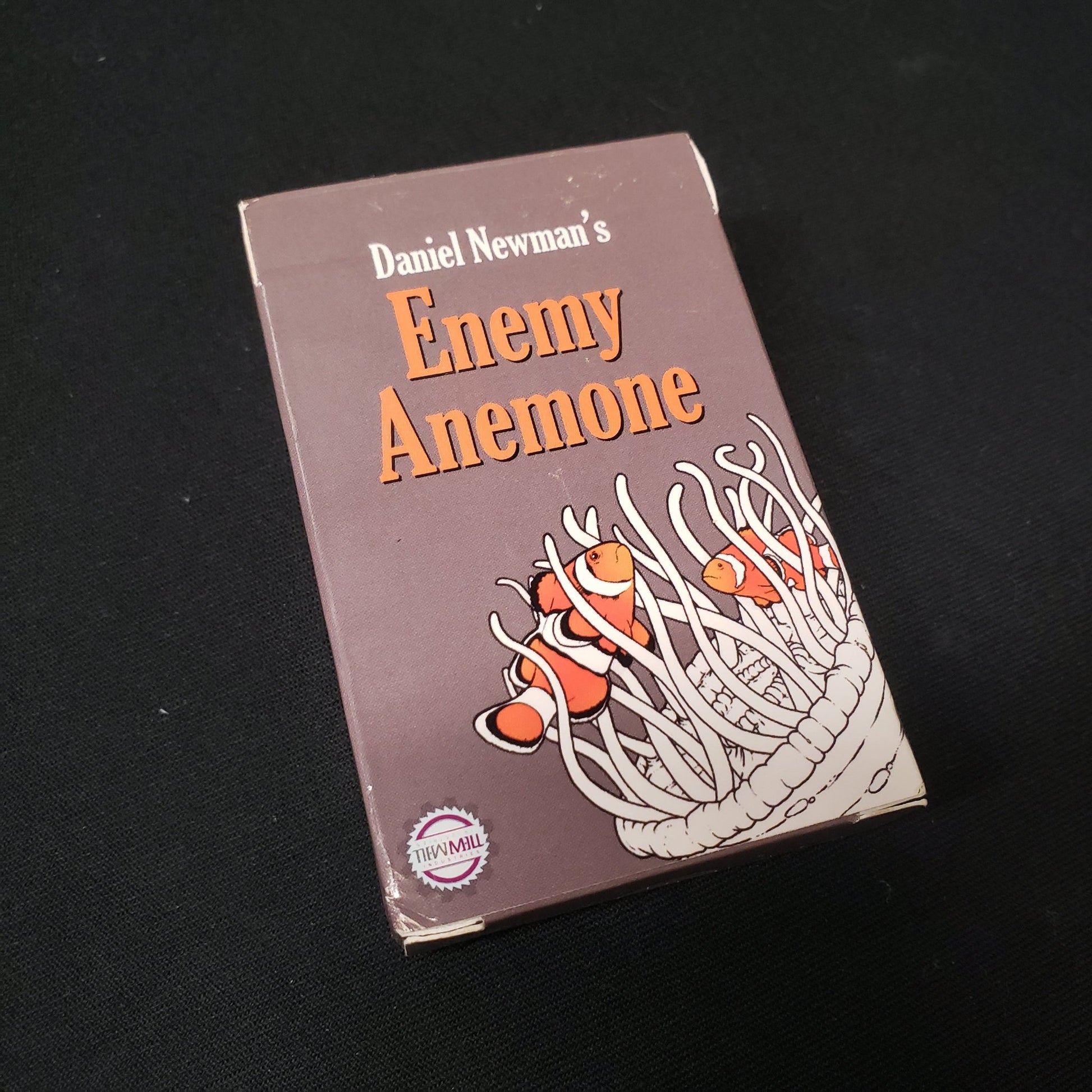 Image shows the front cover of the box of the Enemy Anemone card game
