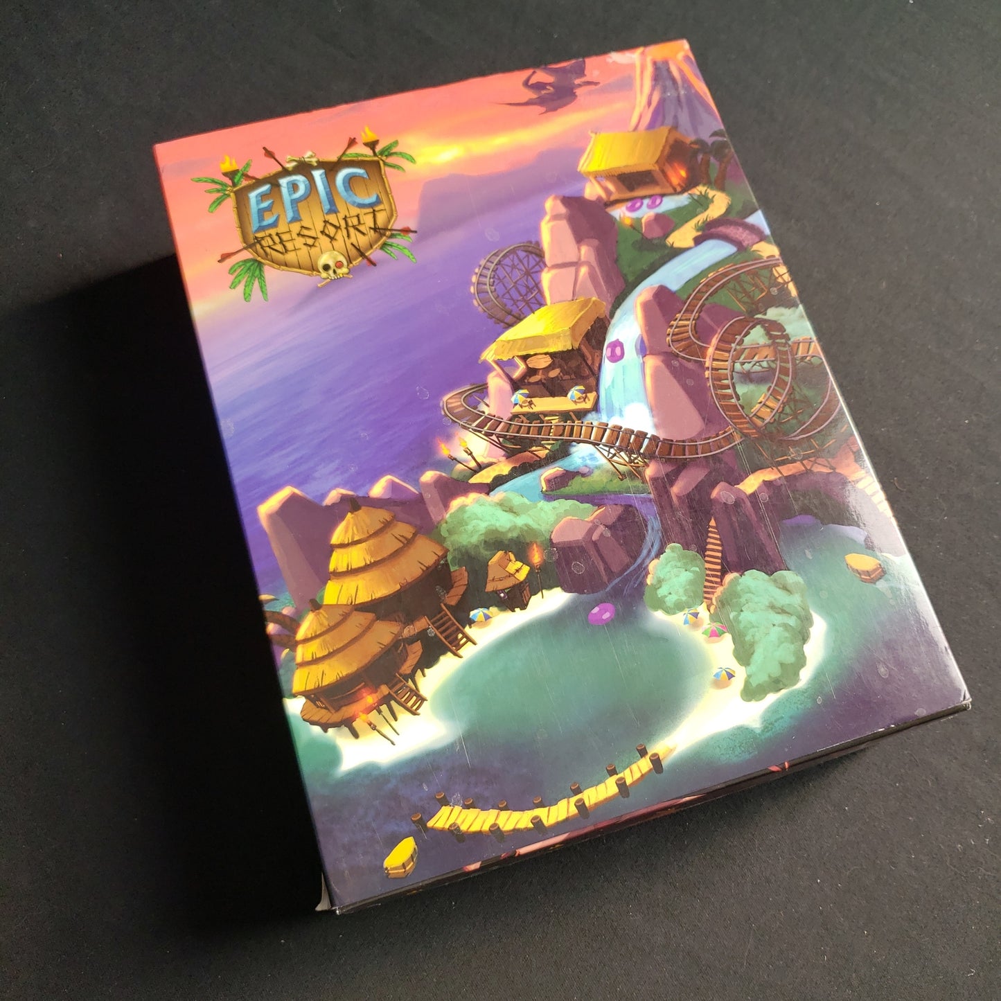 Image shows the front cover of the box of the Epic Resort board game