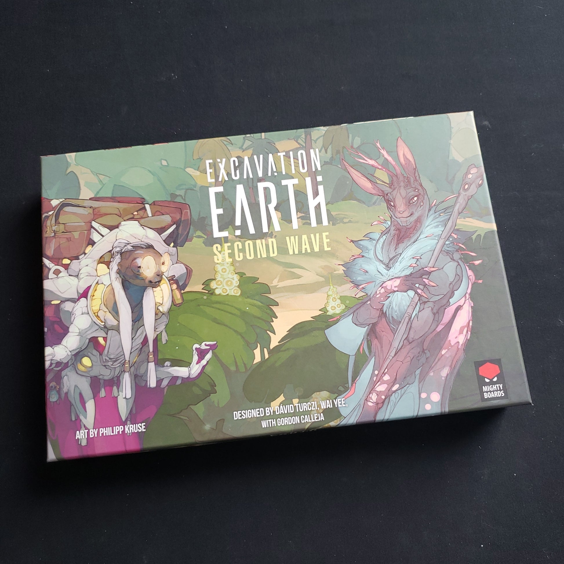 Image shows the front cover of the box of the Second Wave expansion for the board game Excavation Earth