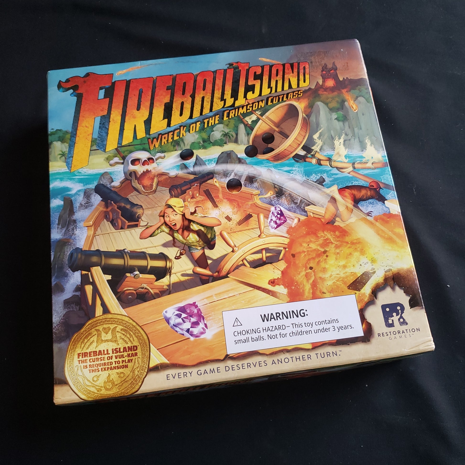 Image shows the front cover of the box of the Wreck of the Crimson Cutlass expansion for the Fireball Island board game