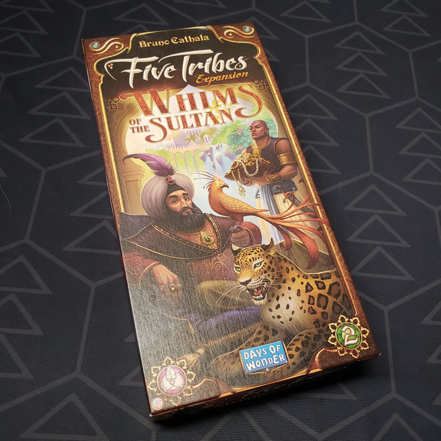 Image shows the front cover of the box of the Whims of the Sultan expansion for the board game Five Tribes