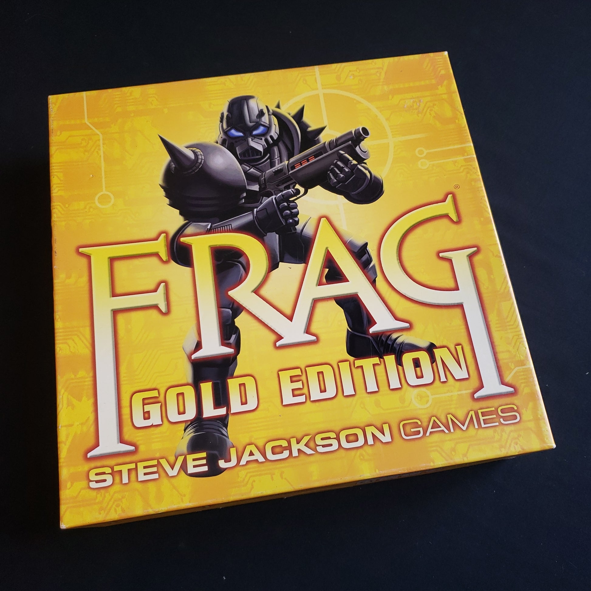 Image shows the front cover of the box of the Frag: Gold Edition board game