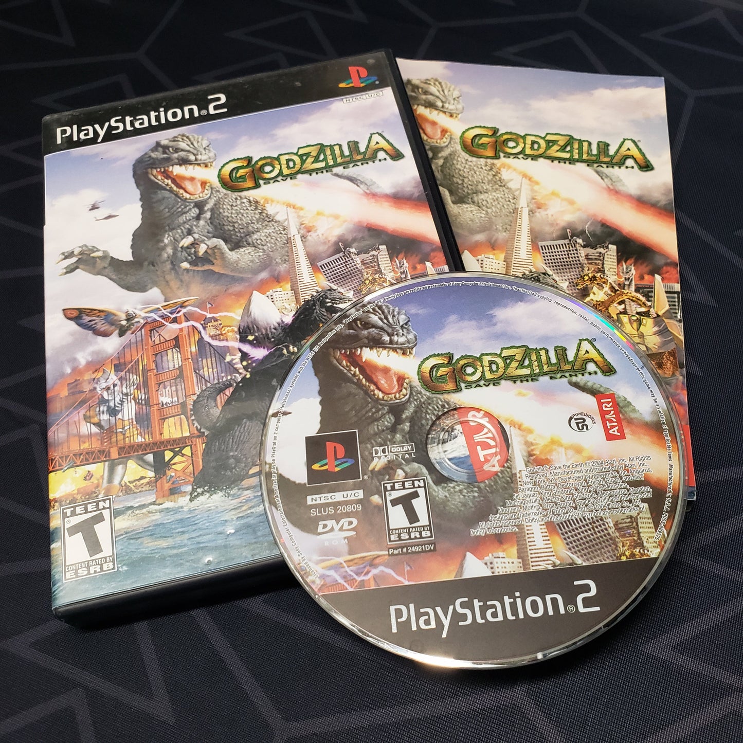 Image shows the case, manual & disc for the video game Godzilla: Save the Earth for Playstation 2