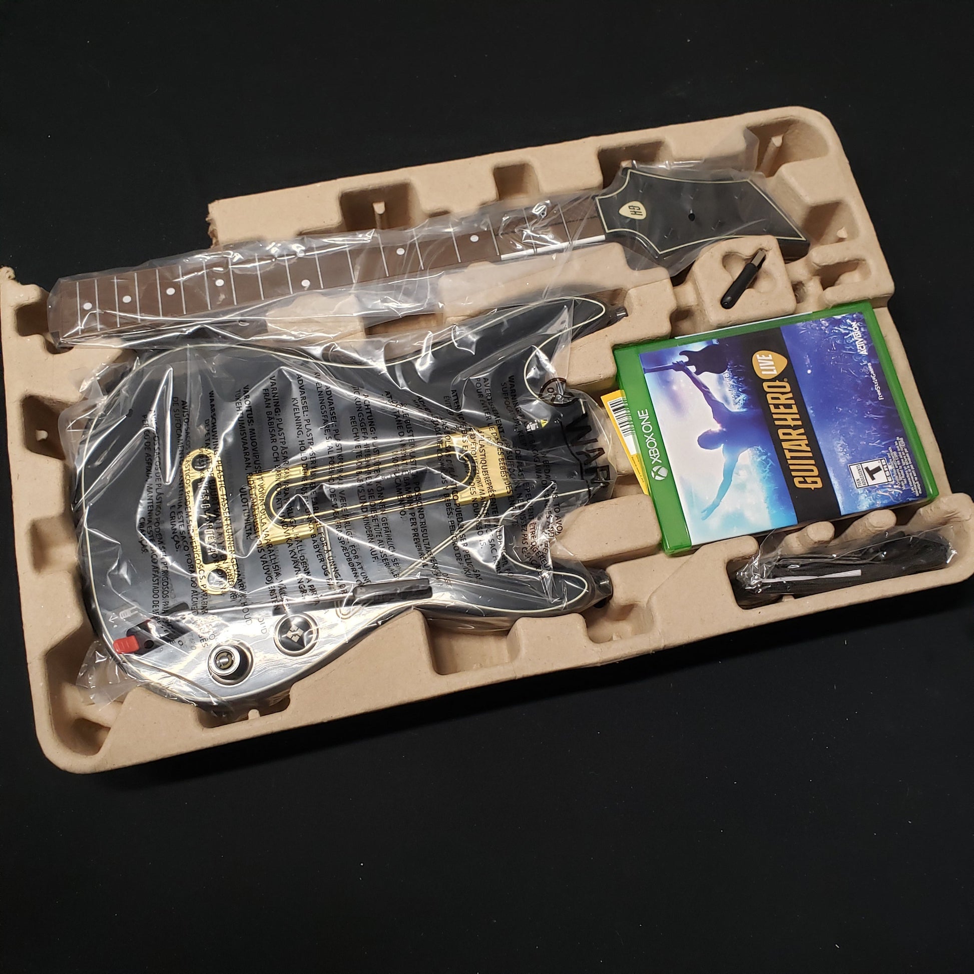 Image shows the contents still in plastic from the guitar bundle box for the video game Guitar Hero Live for Xbox One