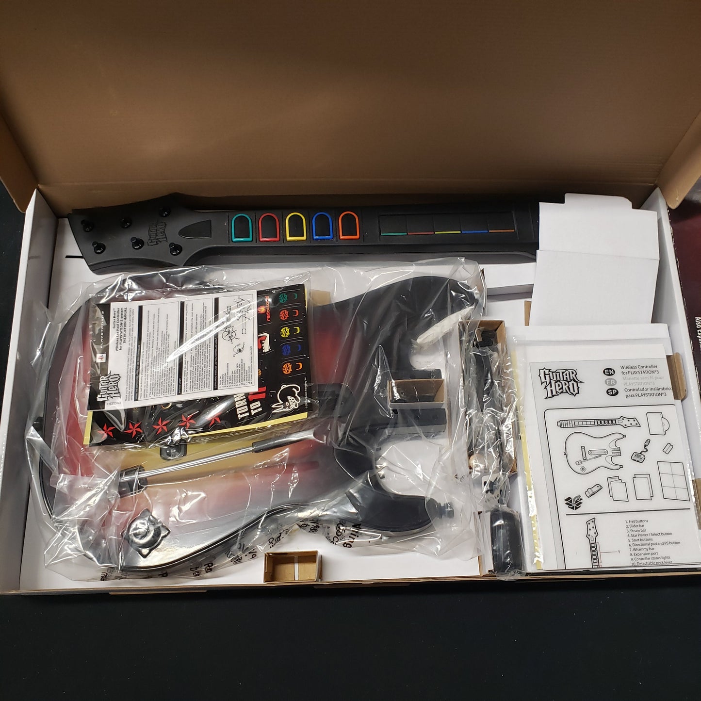 Image shows a Guitar Hero Wireless Guitar video game controller in plastic wrap in its box for Playstation 3
