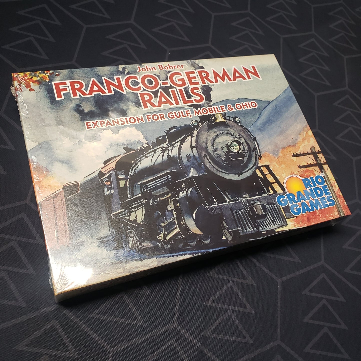 Image shows the front cover of the box of the Franco-German Rails expansion for the board game Gulf, Mobile & Ohio
