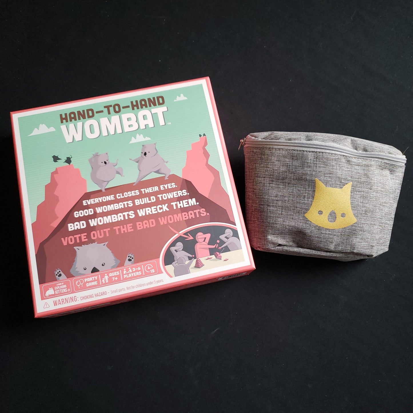 Image shows the front cover of the box & the Golden Wombat pouch for the Hand-To-Hand Wombat game