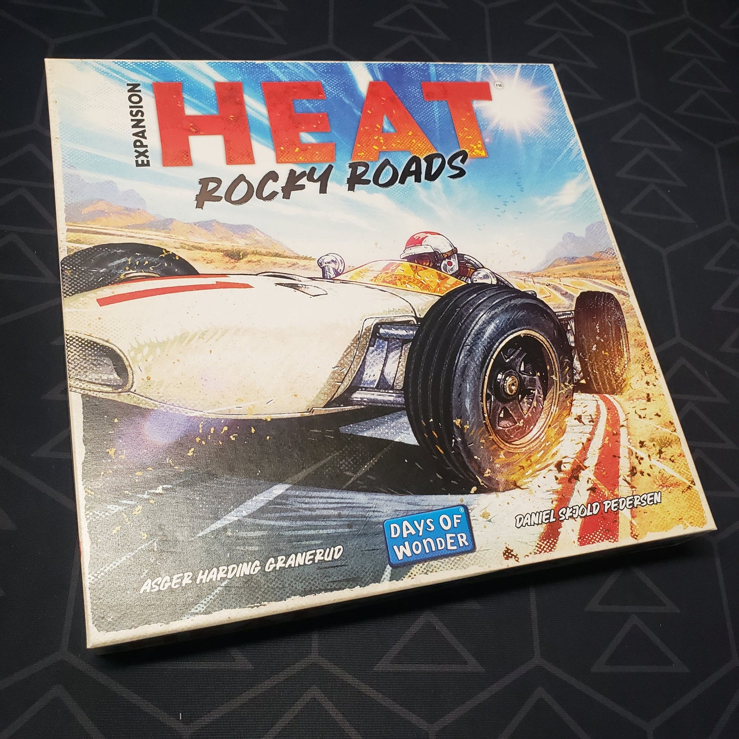 Image shows the front cover of the box of the Rocky Roads expansion for the board game Heat
