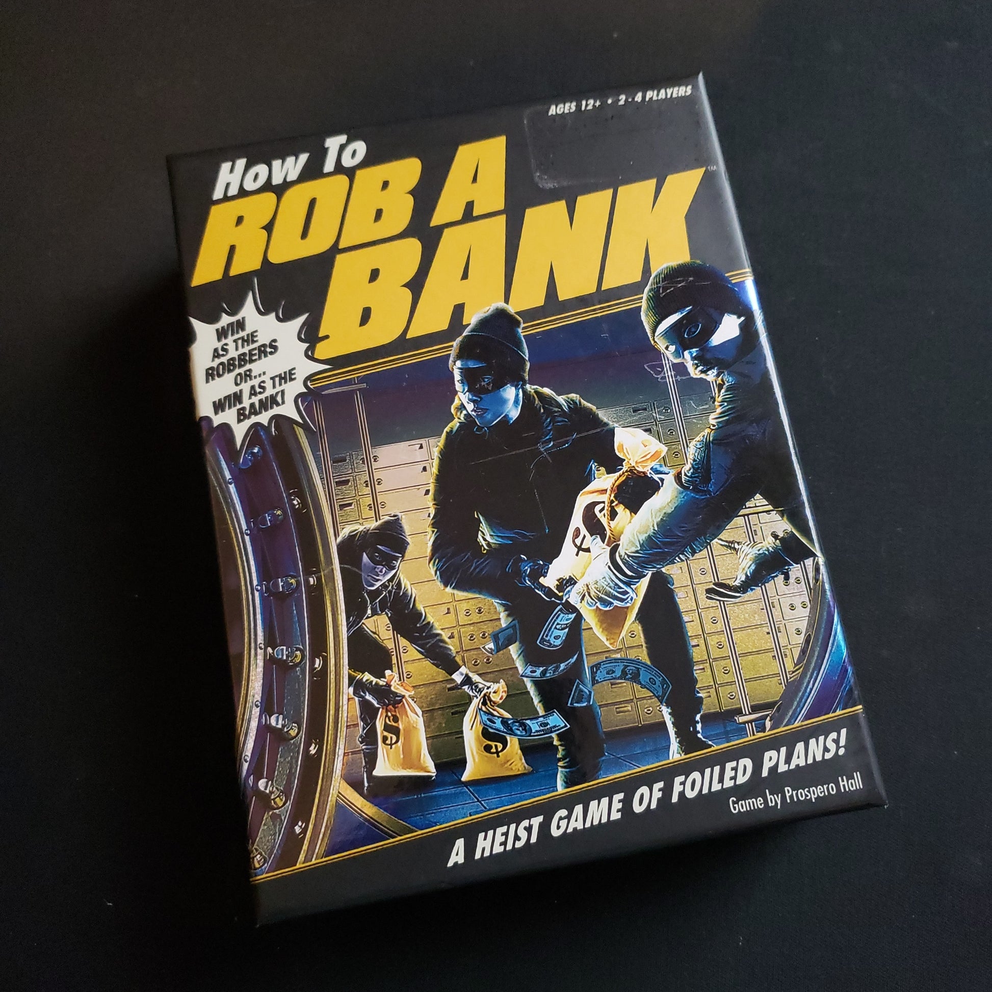 Image shows the front cover of the box of the How to Rob a Bank card game