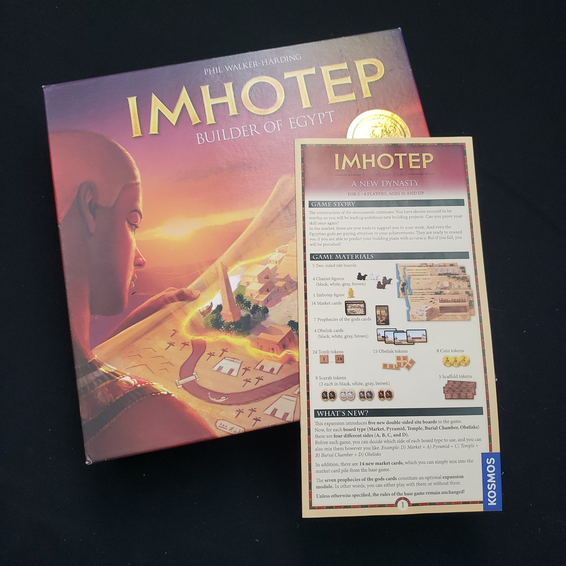 Image shows the front cover of the box of the Imhotep board game, with the instructions for the New Dynasty expansion sitting on top of it