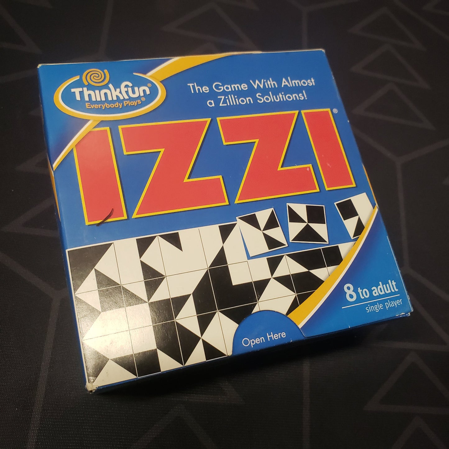 Image shows the front cover of the box for the IZZI puzzle game