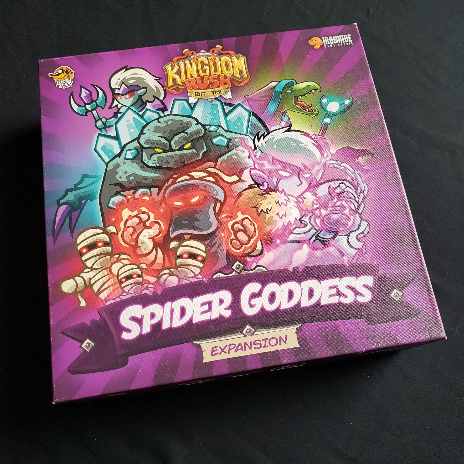 Image shows the front cover of the box of the Spider Goddess expansion for the Kingdom Rush: Rift in Time board game