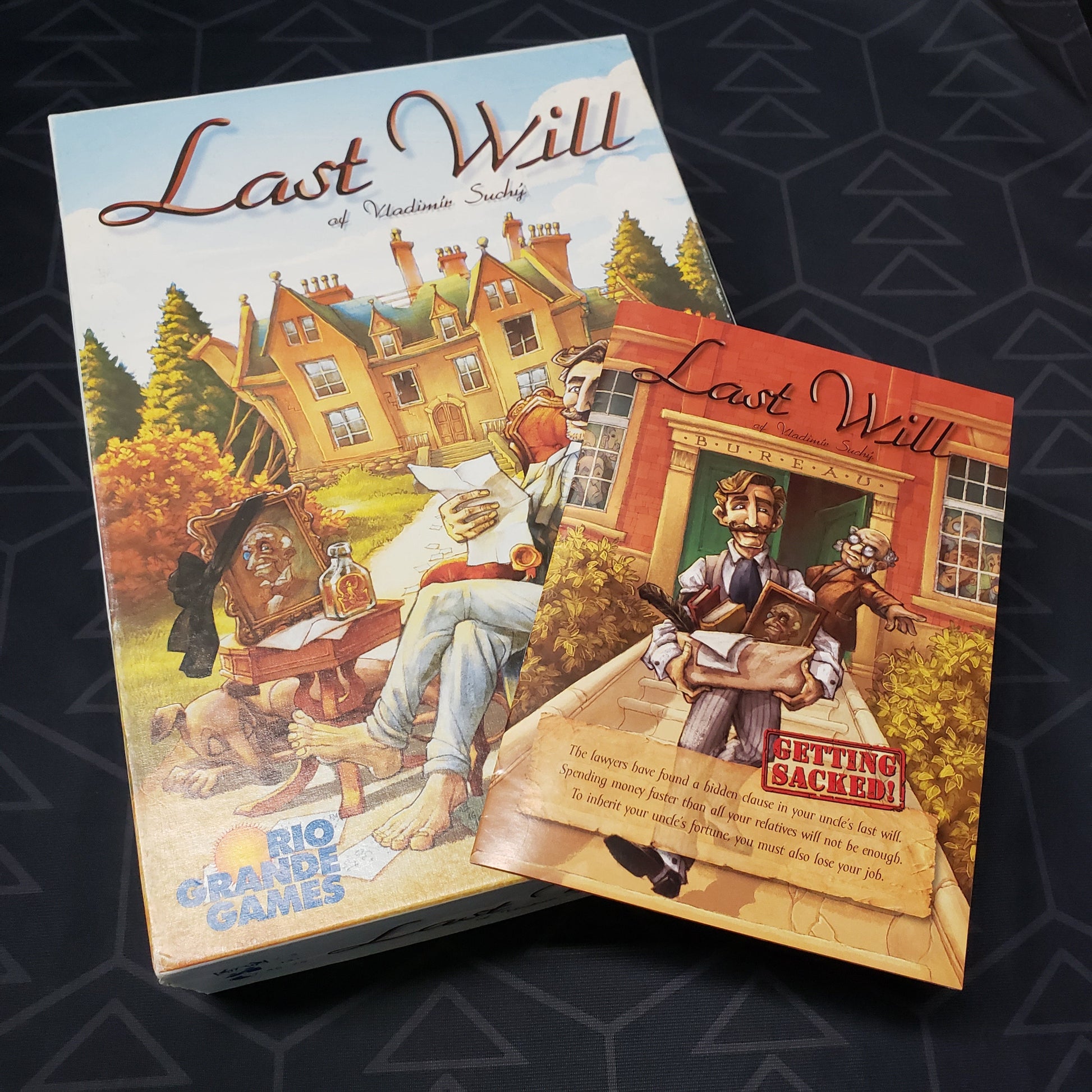 Image shows the front cover of the box for the Last Will board game with the instructions for the Getting Sacked expansion sitting on top of it