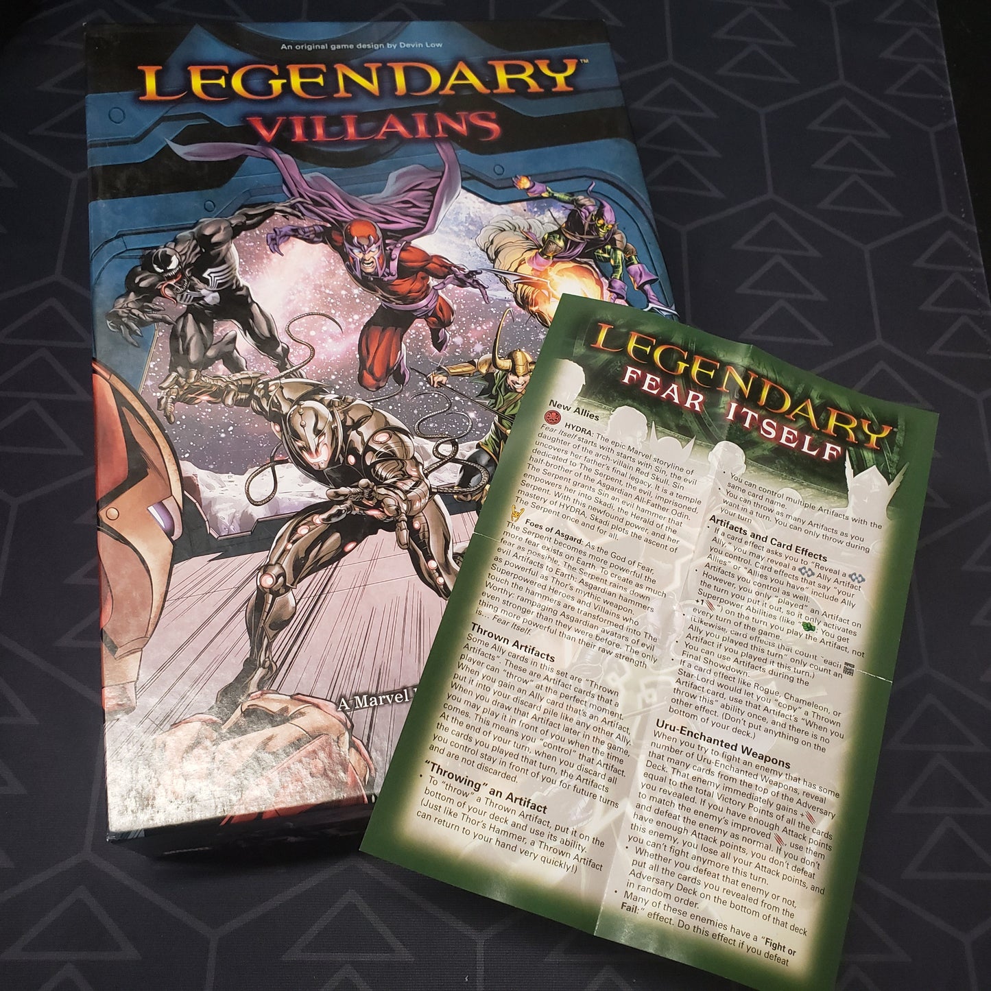 Image shows the front cover of the box for the Legendary Marvel: Villains card game with the instruction sheet for the Fear Itself expansion sitting on top of it
