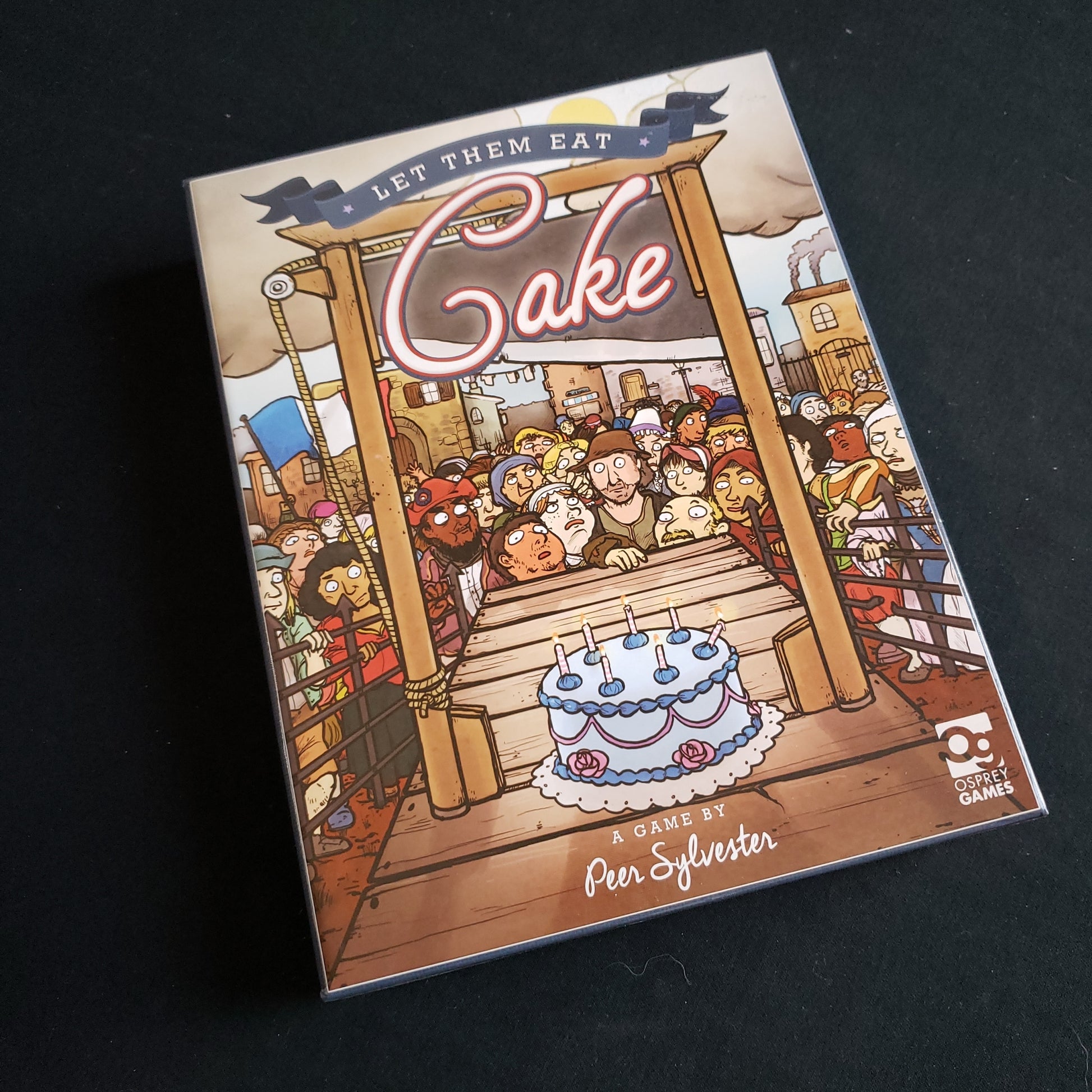 Image shows the front cover of the box of the Let Them Eat Cake board game