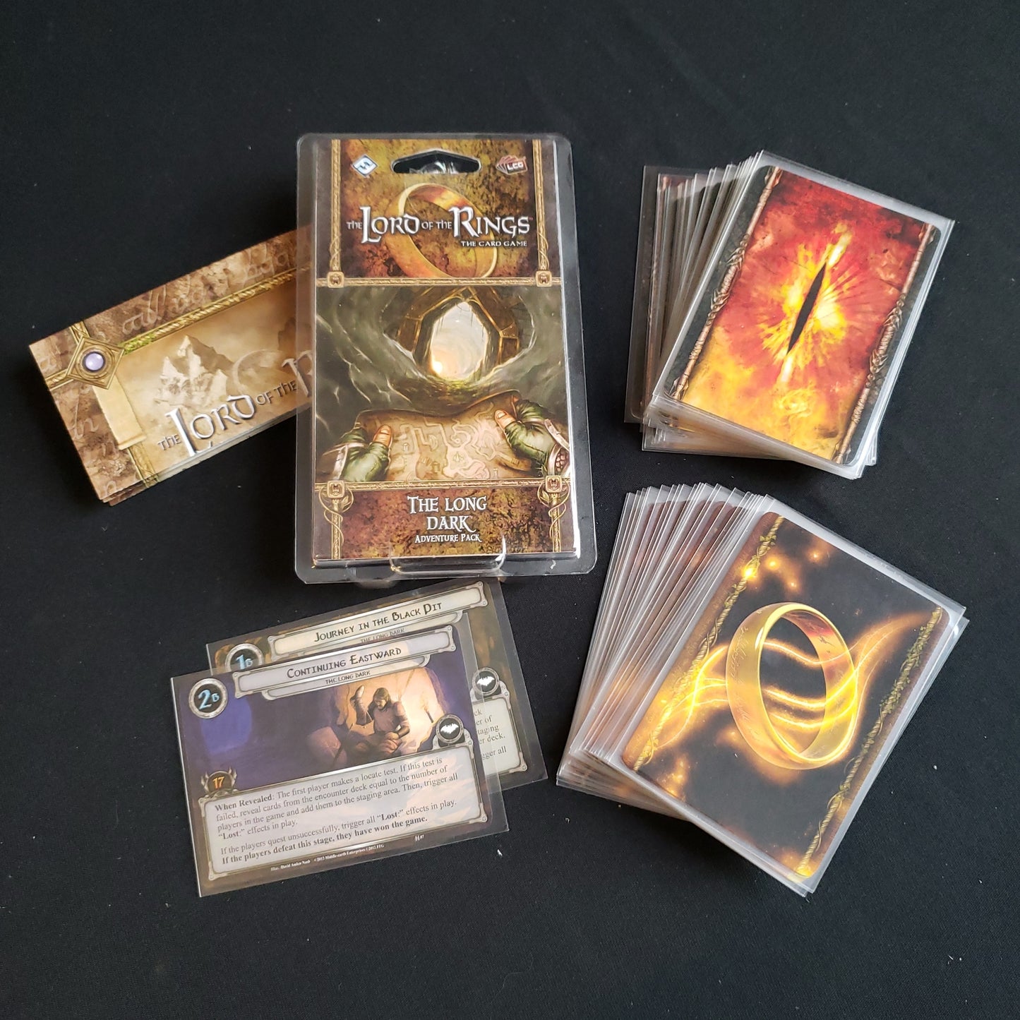 Image shows the front of the package for the Long Dark Adventure Pack for the Lord of the Rings card game, with the cards and instructions fanned out around it