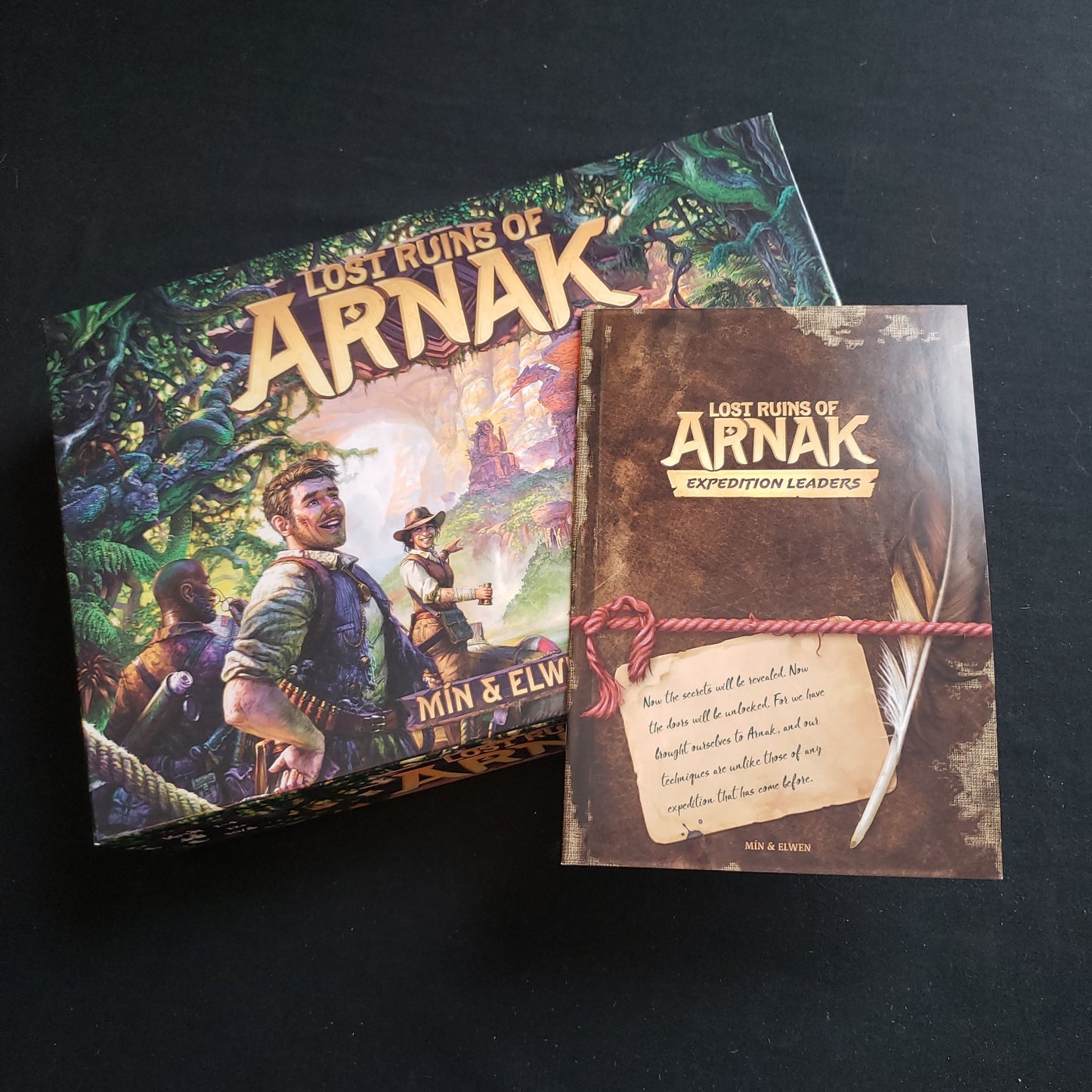 Image shows the front cover of the box of the Lost Ruins of Arnak board game, with the instructions for the Expedition Leaders expansion sitting on top of it