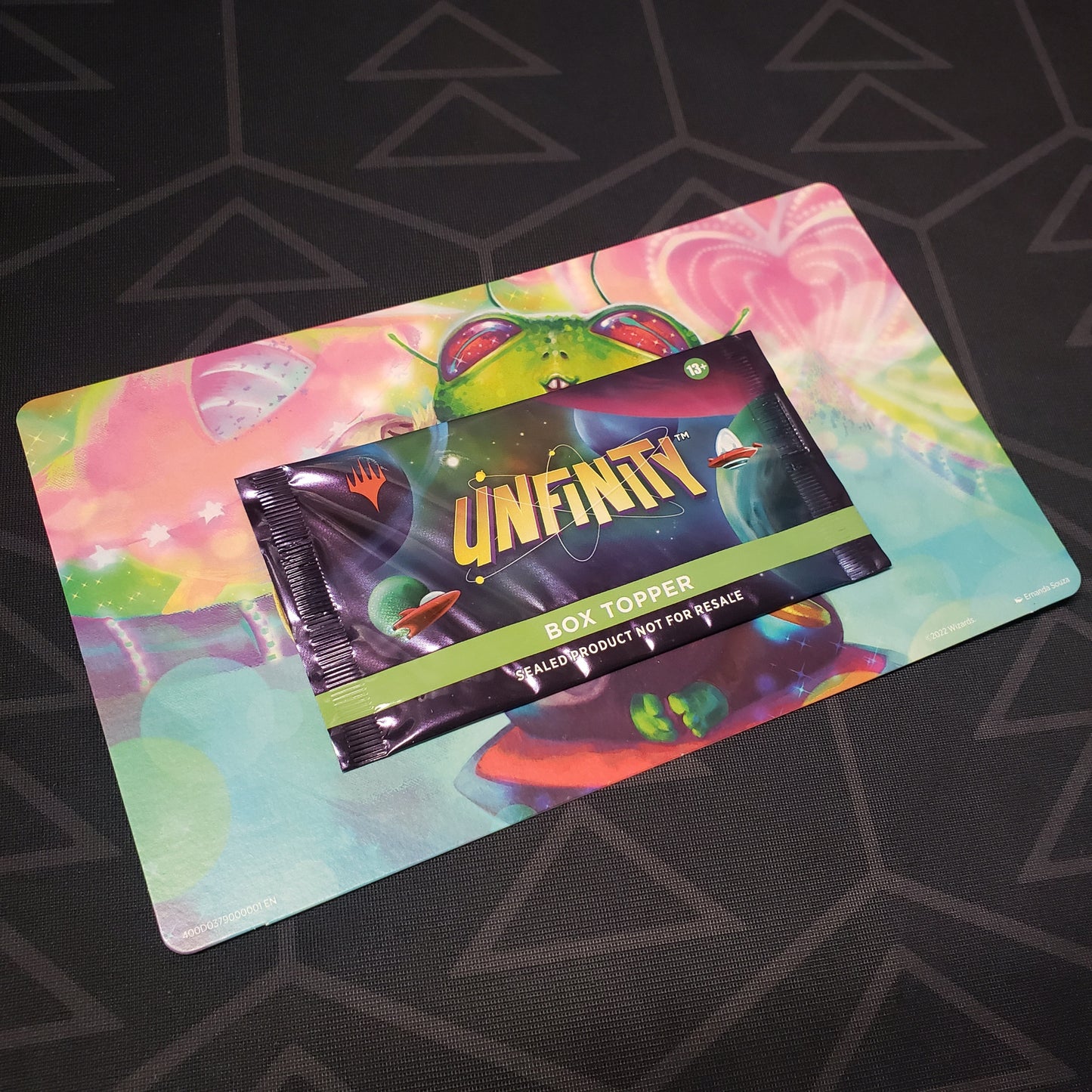 Image shows the front of the packaging of an Unfinity: Box Topper Pack for the card game Magic the Gathering still mounted on its backer cardboard