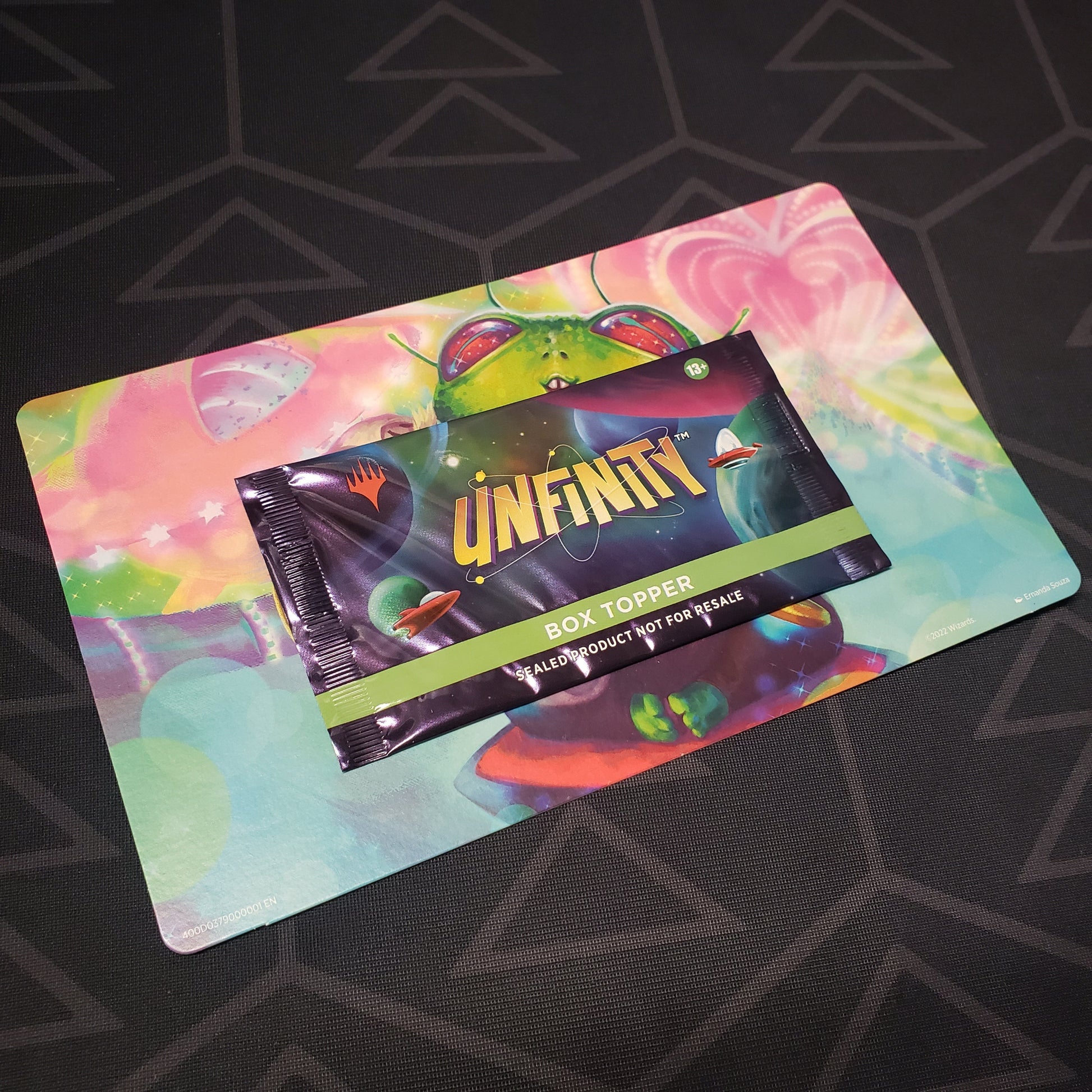 Image shows the front of the packaging of an Unfinity: Box Topper Pack for the card game Magic the Gathering still mounted on its backer cardboard