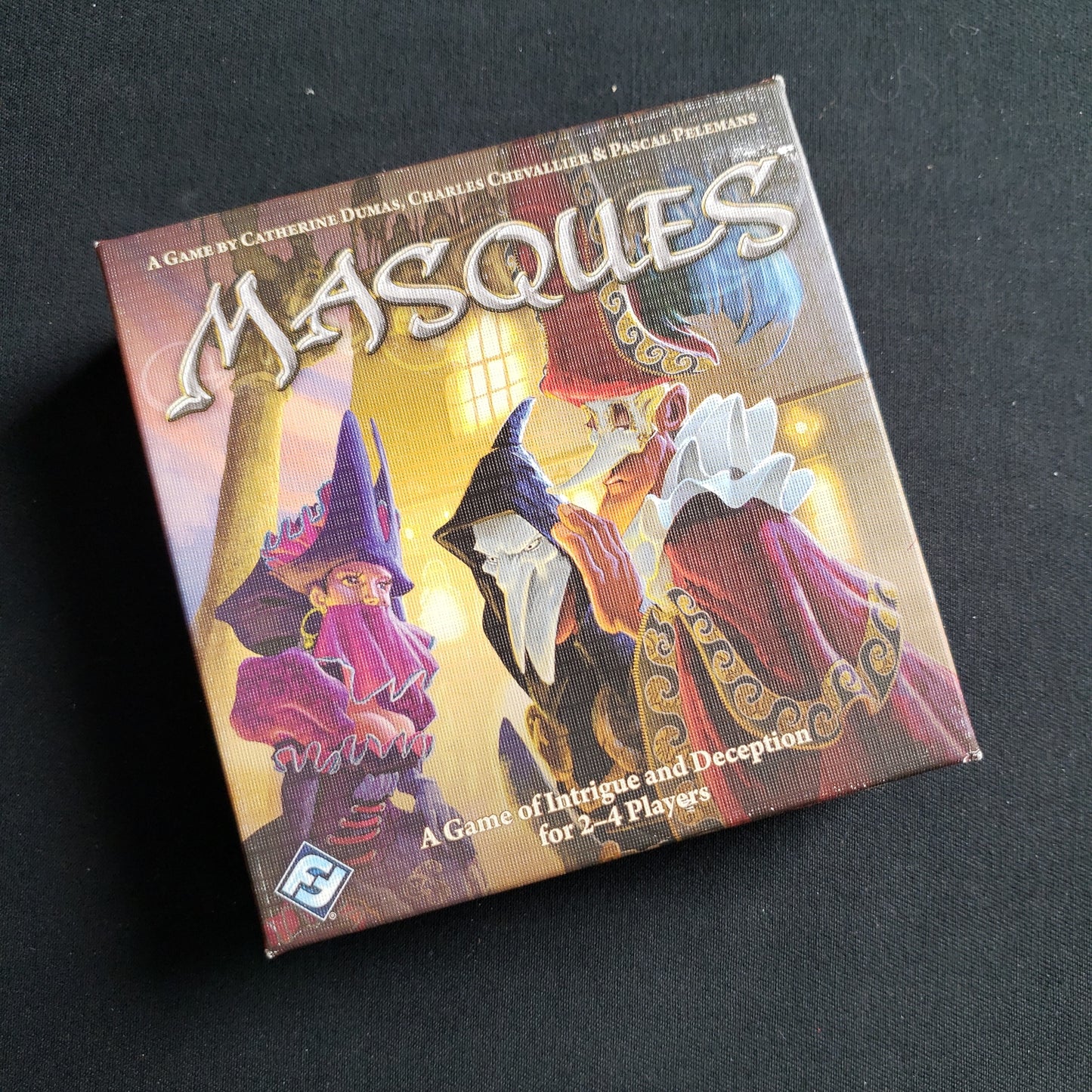 Image shows the front cover of the box of the Masques card game