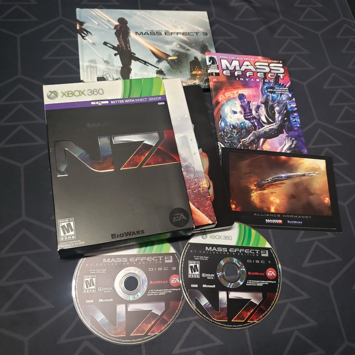 Image shows the cases, extras and two discs for the N7 Collector's Edition of the video game Mass Effect 3 for Xbox 360
