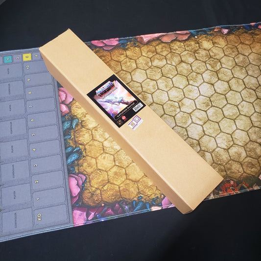 Image shows the box for the playmat for the Masters of the Universe: Clash for Eternia board game sitting on top of the nrolled playmat
