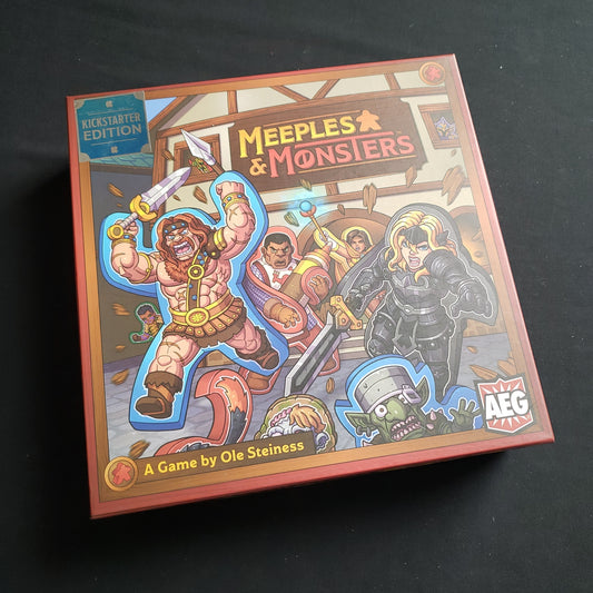 Image shows the front cover of the box of the Meeples and Monsters board game