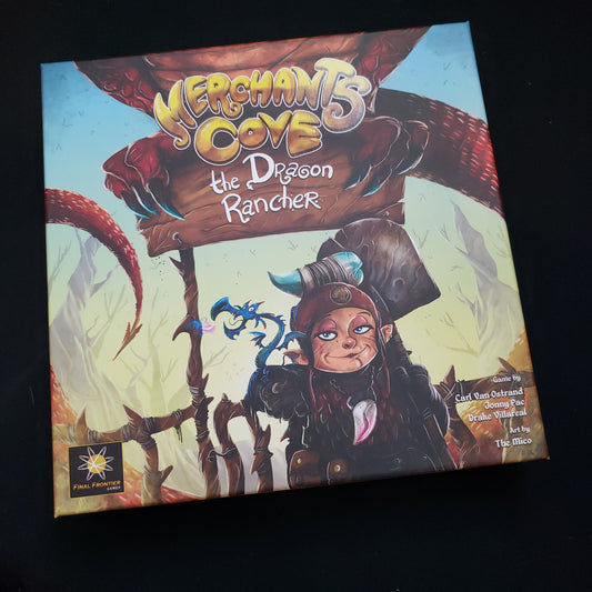 Image shows the front cover of the box of the Dragon Rancher expansion for the board game Merchants Cove
