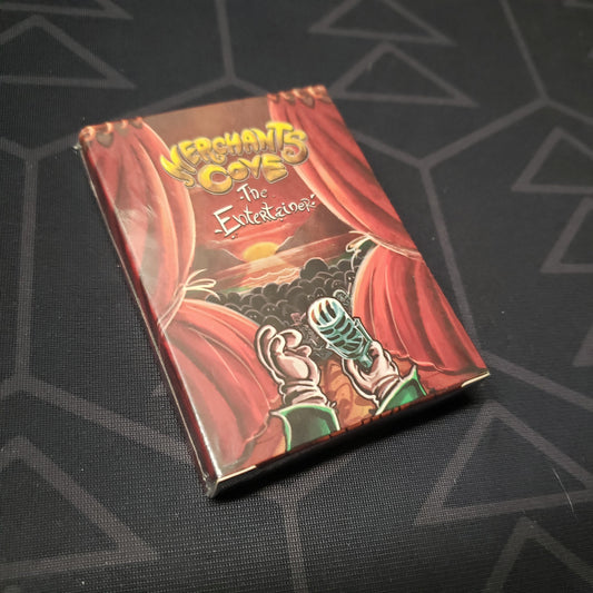 Image shows the front cover of the box of the Entertainer Crossover Pack expansion for the board game Merchants Cove