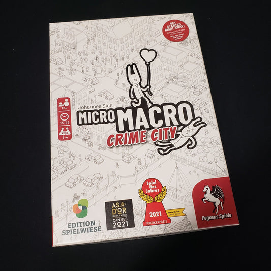 Image shows the front cover of the box of the MicroMacro: Crime City board game